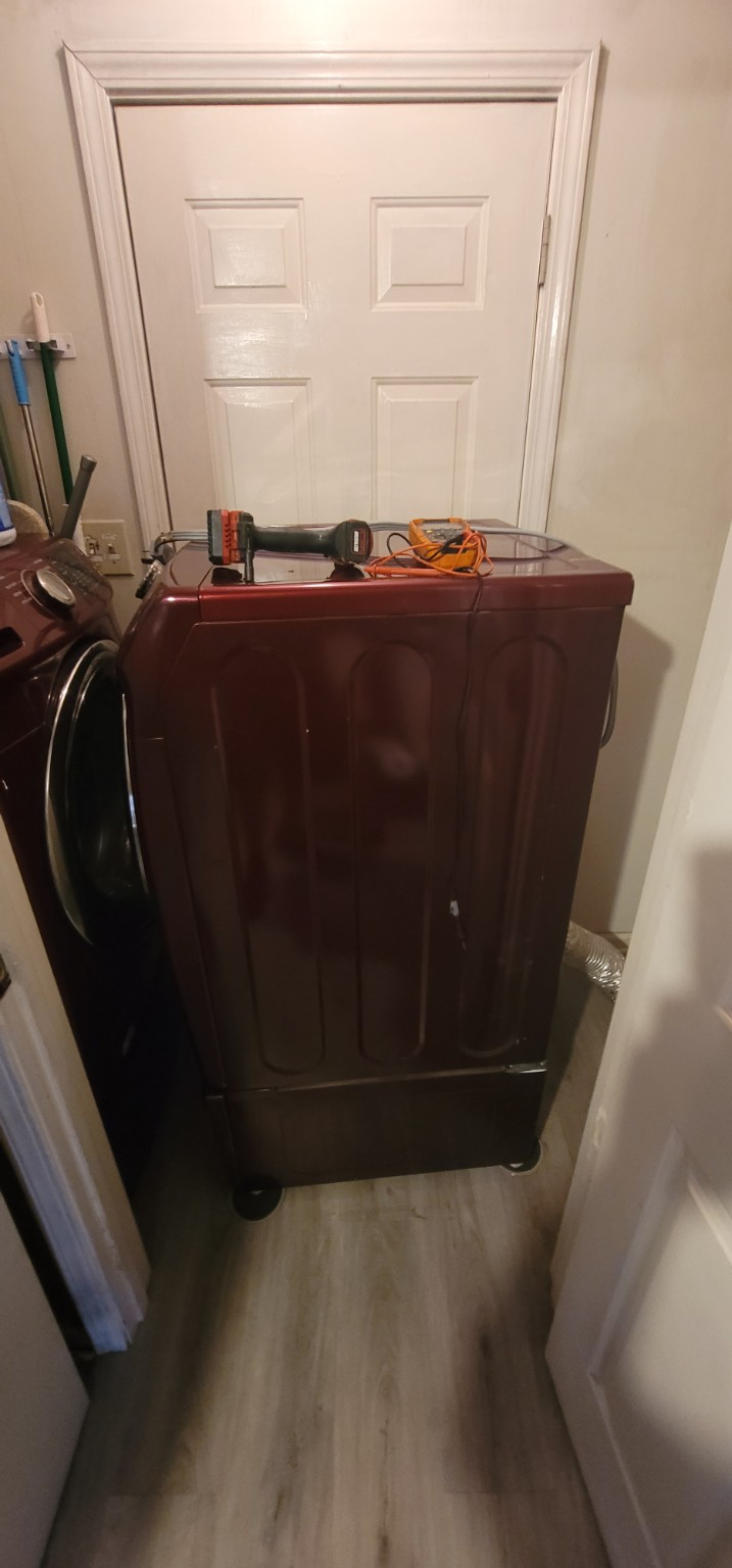 Dryer positioned for service with a drill and multimeter on top.