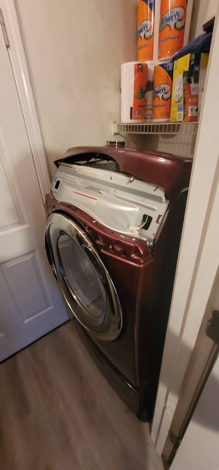 Burgundy front-load dryer partially disassembled during a repair.