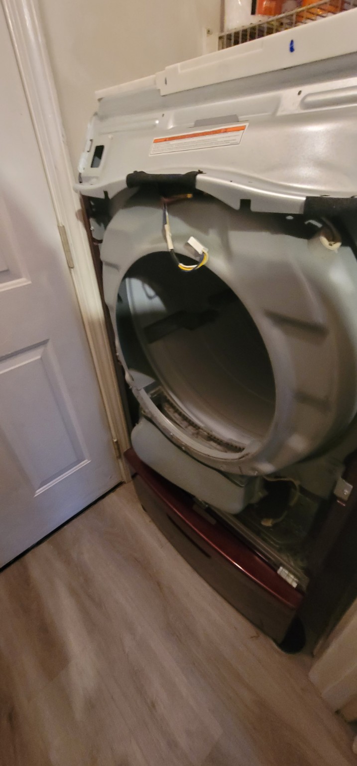 Dryer with the front panel removed and the drum visible during service.